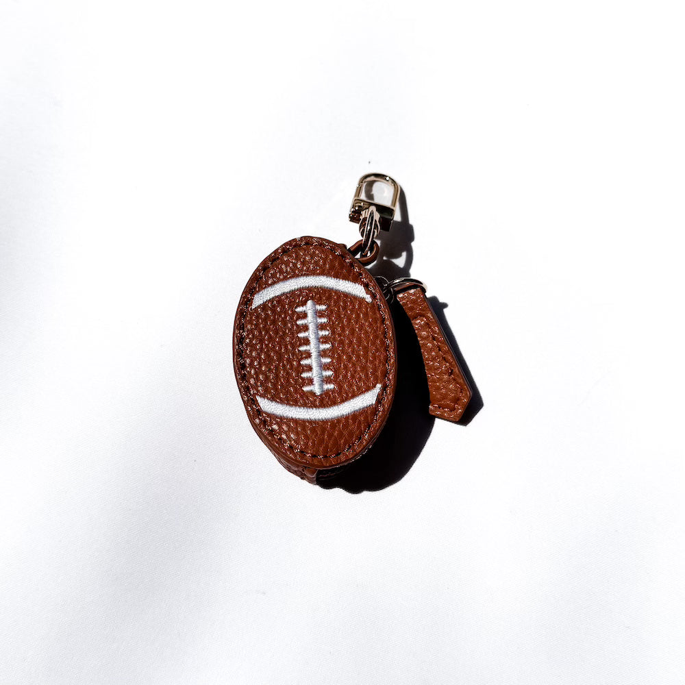 Brown leather sports bag charm ball with white laces on a gold keyring clip