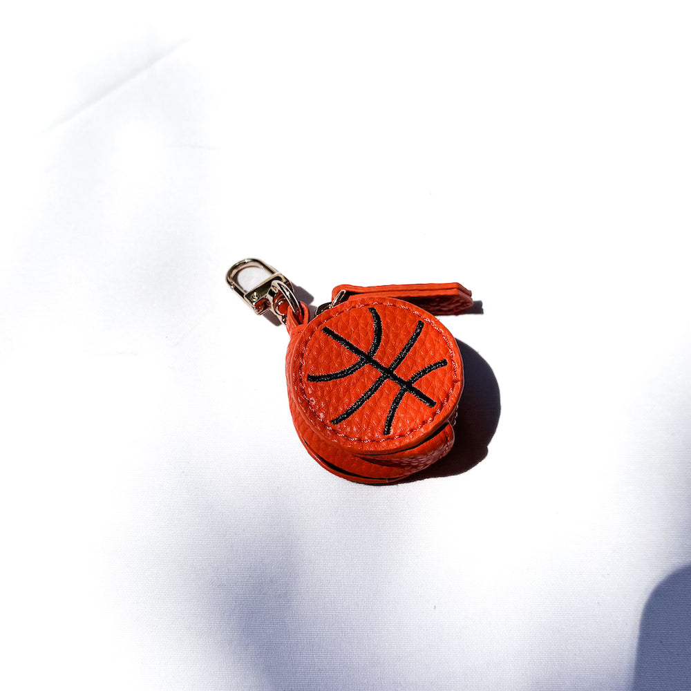 Orange sports bag charm ball with black basketball lines and a gold keyring clip