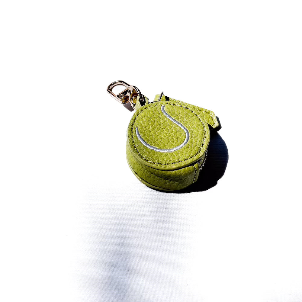 Green sports bag charm ball with white curved lines on a gold keyring clip
