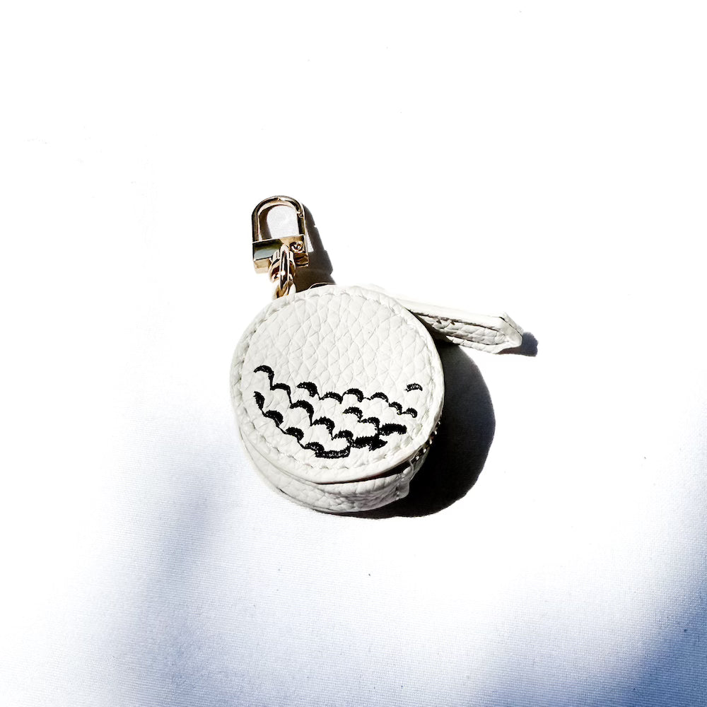 White sports bag charm with black batting-swing stitches on a gold keyring clip