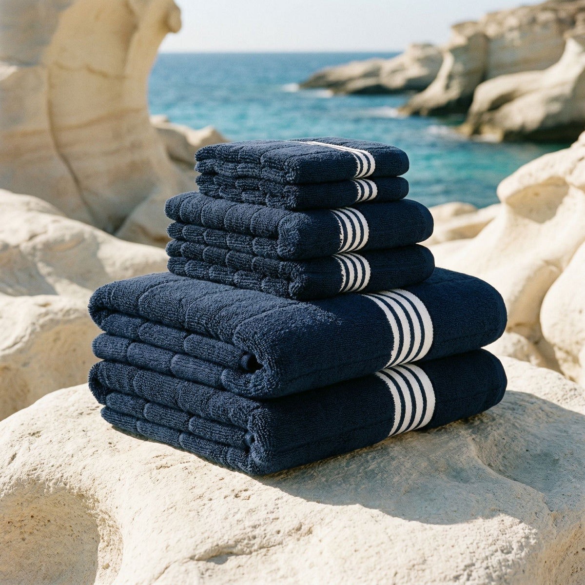 Stack of navy cotton towels with white striped bands