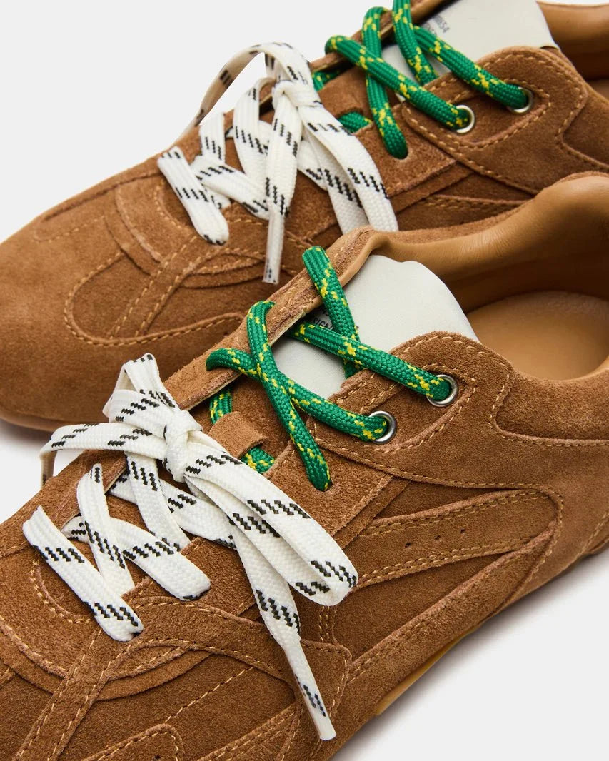 Camel suede sneakers close-up with green laces, white graphic lace ties, and stitching