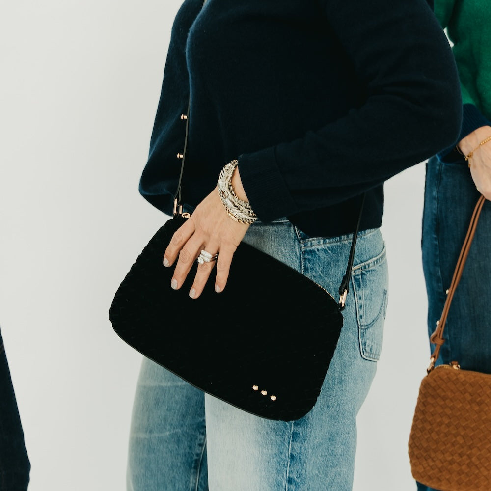 Black suede hobo shoulder bag with quilted texture and top zipper, worn crossbody