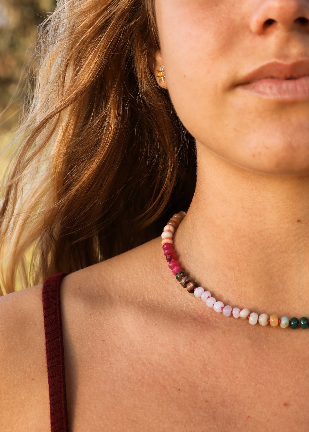 Multi-color gemstone beaded necklace with gold toggle clasp, worn close-up on neck.