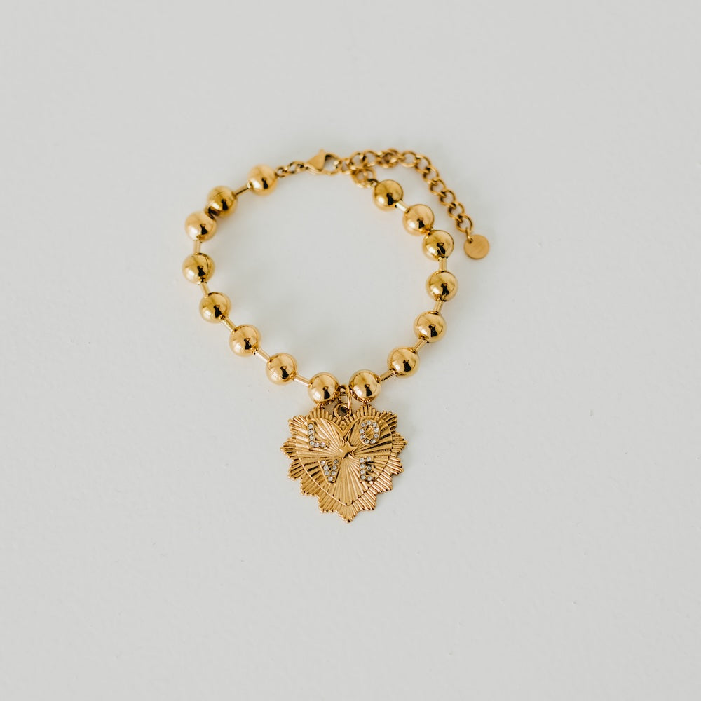 Gold-tone beaded bracelet with dangling sunburst heart pendant