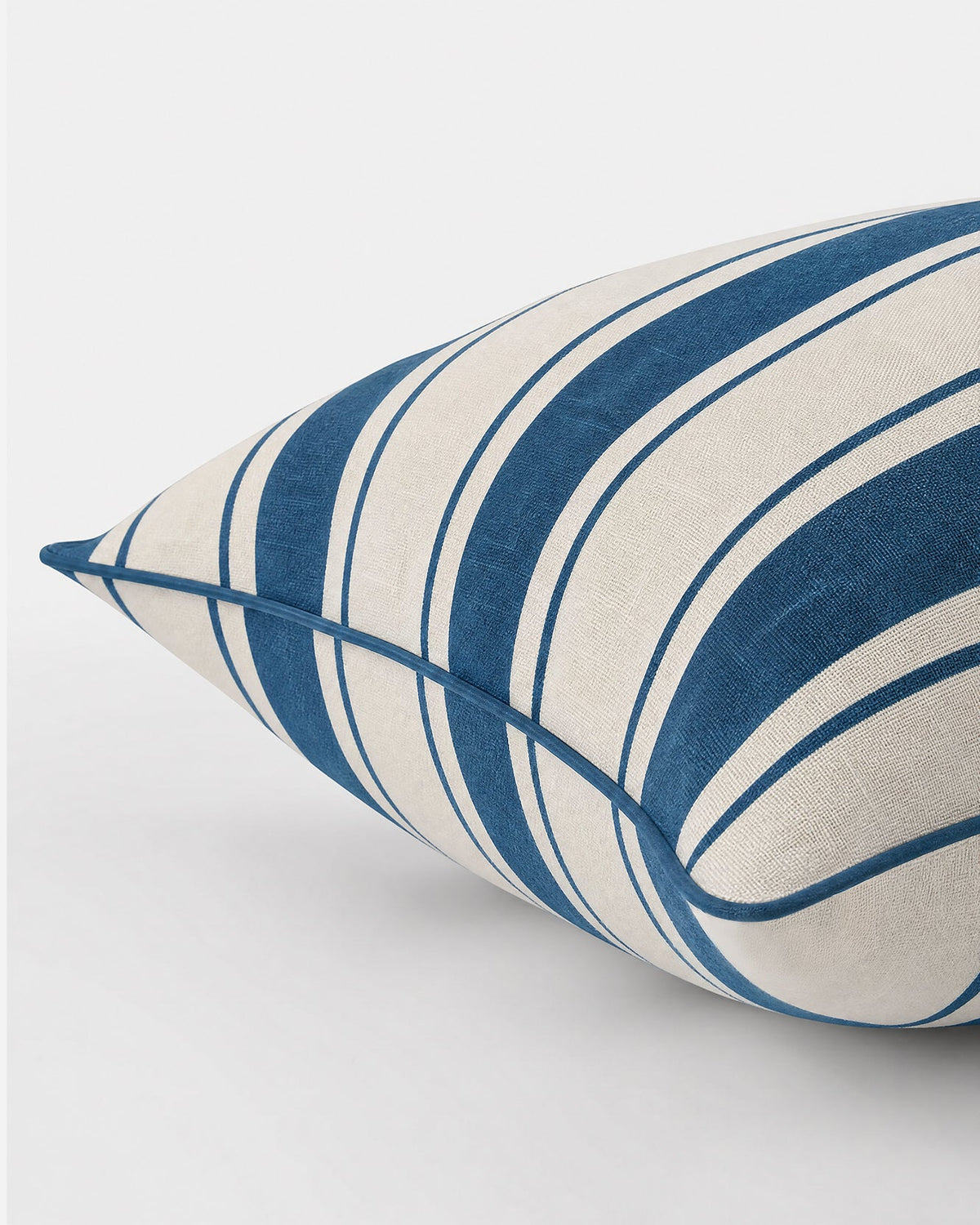 Lumbar pillow close-up: ivory cover with dark blue and light blue vertical stripes