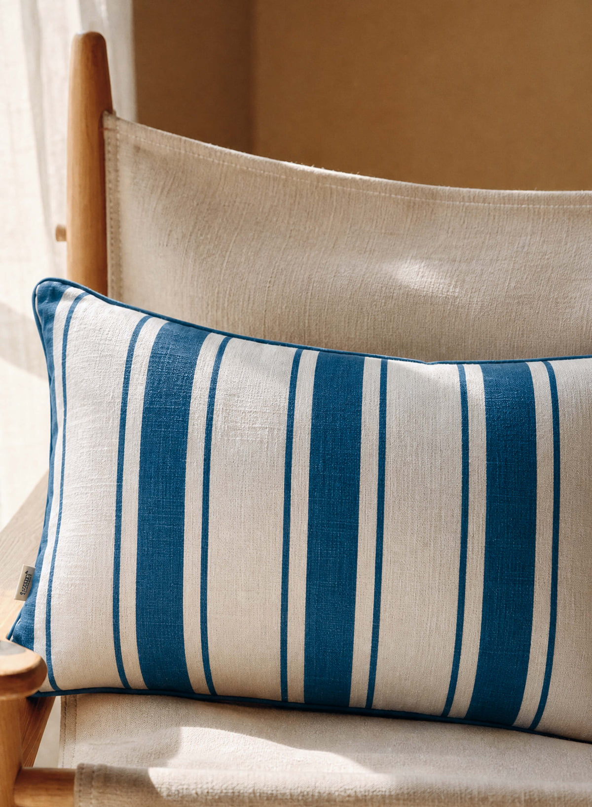 Lumbar pillow in ivory with blue vertical stripe fabric and piped border