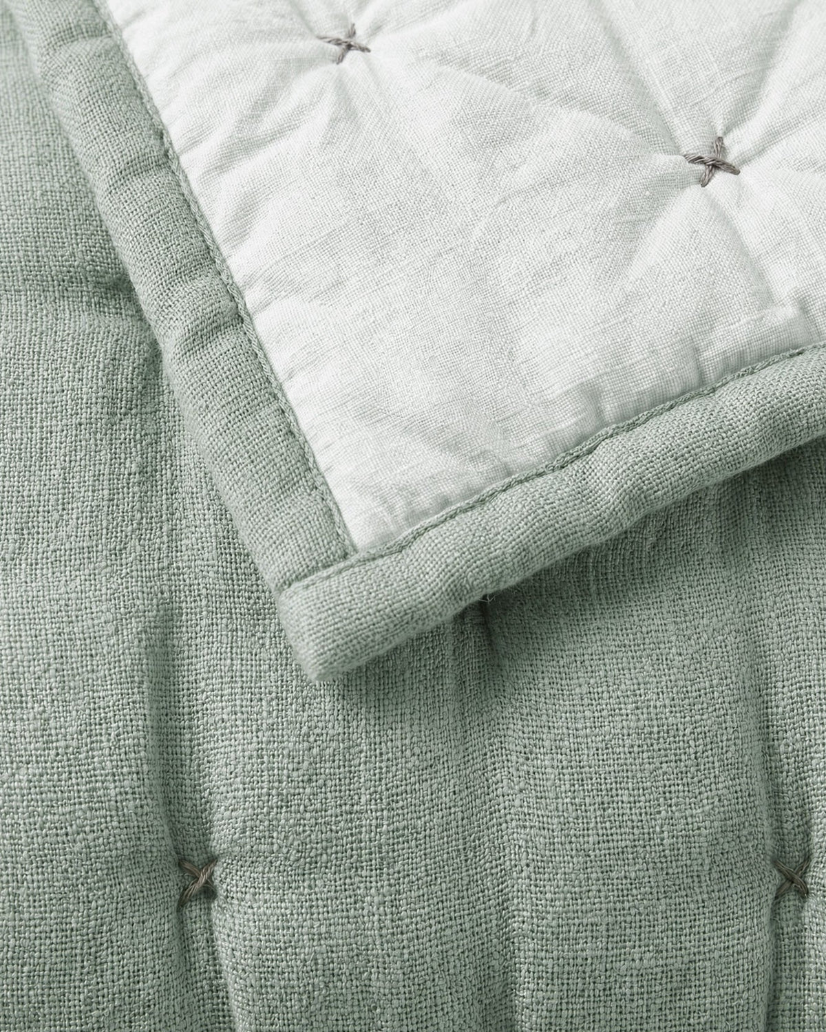 Misty blue quilt corner detail with contrast stitching and pin-tuck knot details