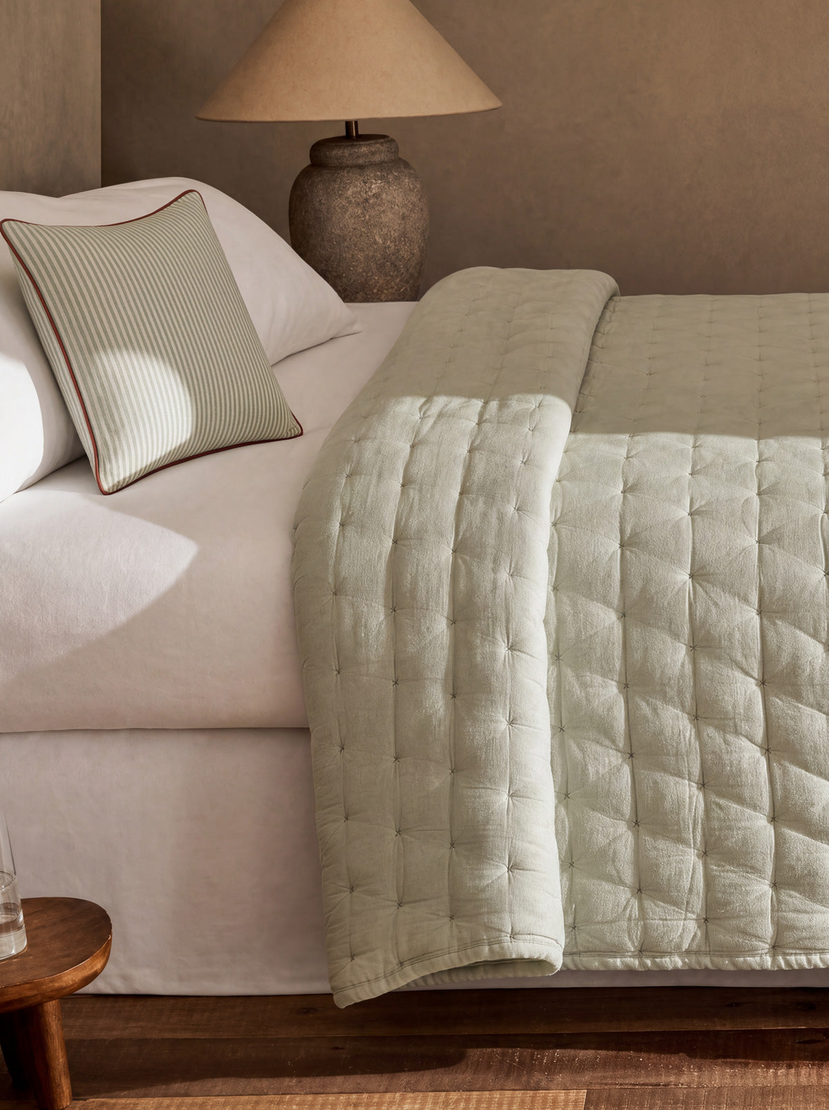 Taupe quilted bedspread with channel stitching and stitched tufted square panels