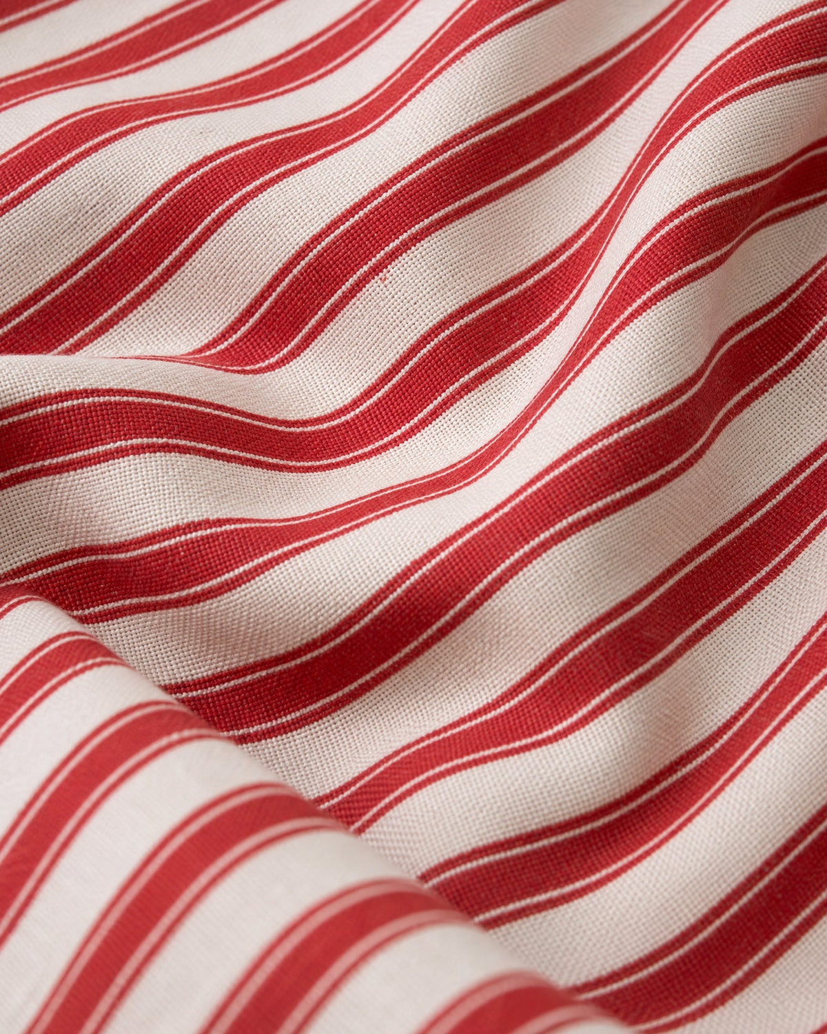 Red and off-white striped tablecloth fabric with woven texture, close-up.