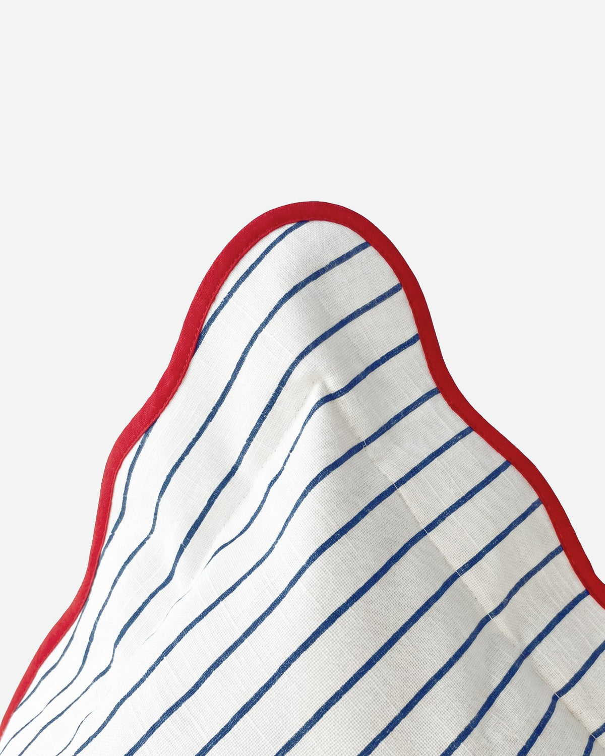 Close-up of blue-and-white striped throw pillow corner with red wavy trim piping.