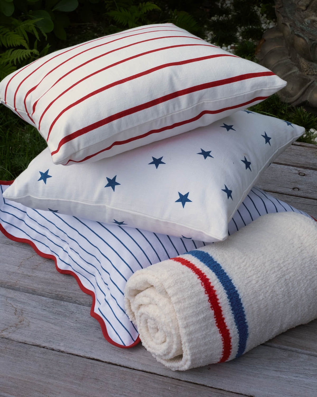 Stack of throw pillows: blue star print and blue-striped designs with red wavy trim.