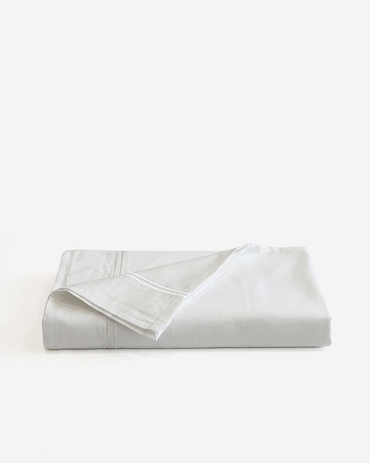 White cotton sateen embroidered top sheet, folded with stitched border and corner hems.