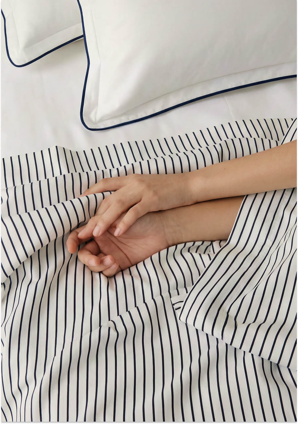 Striped cooling top sheet with hands smoothing the surface on the corner