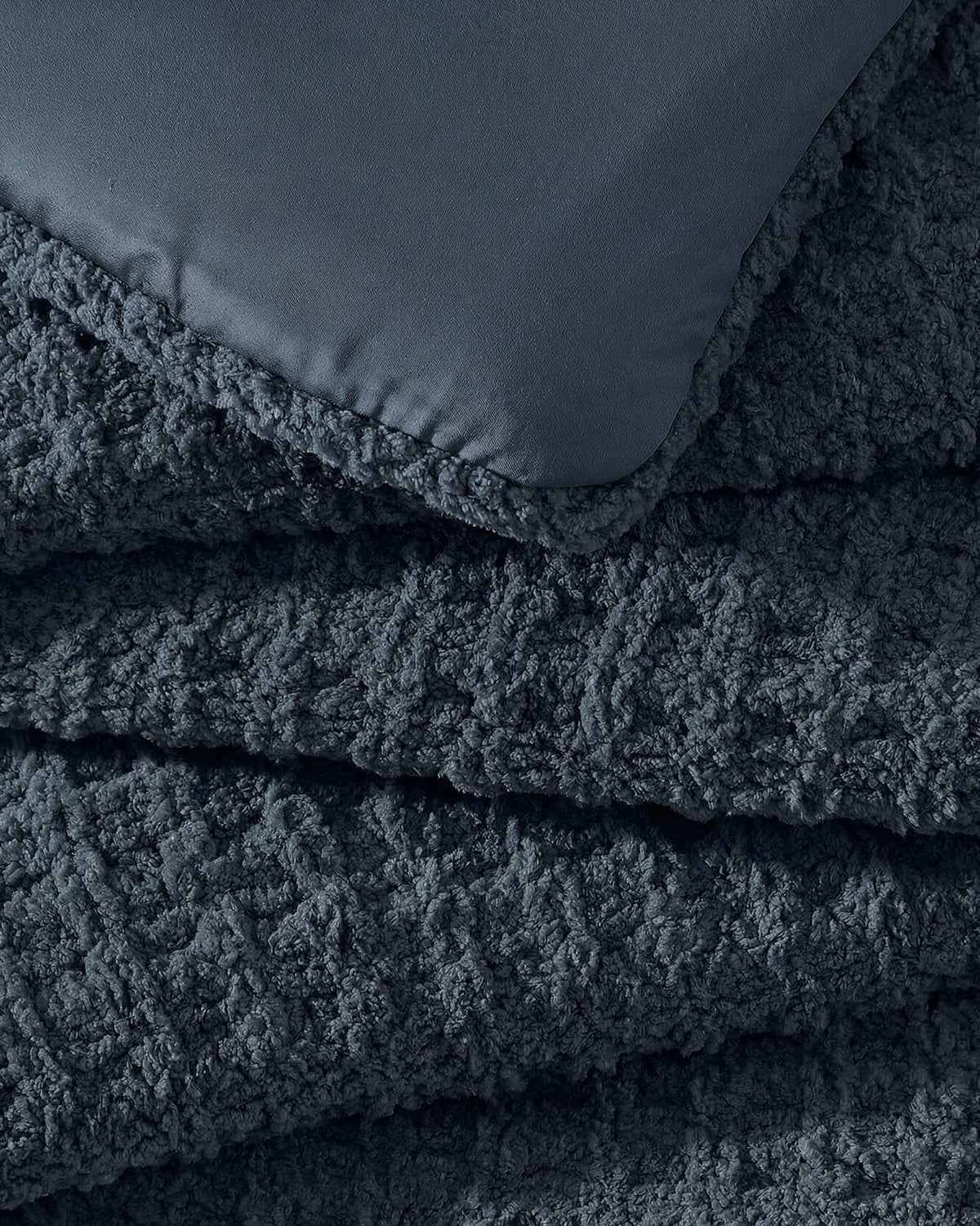 Midnight blue waffle comforter fabric close-up with stitched edge