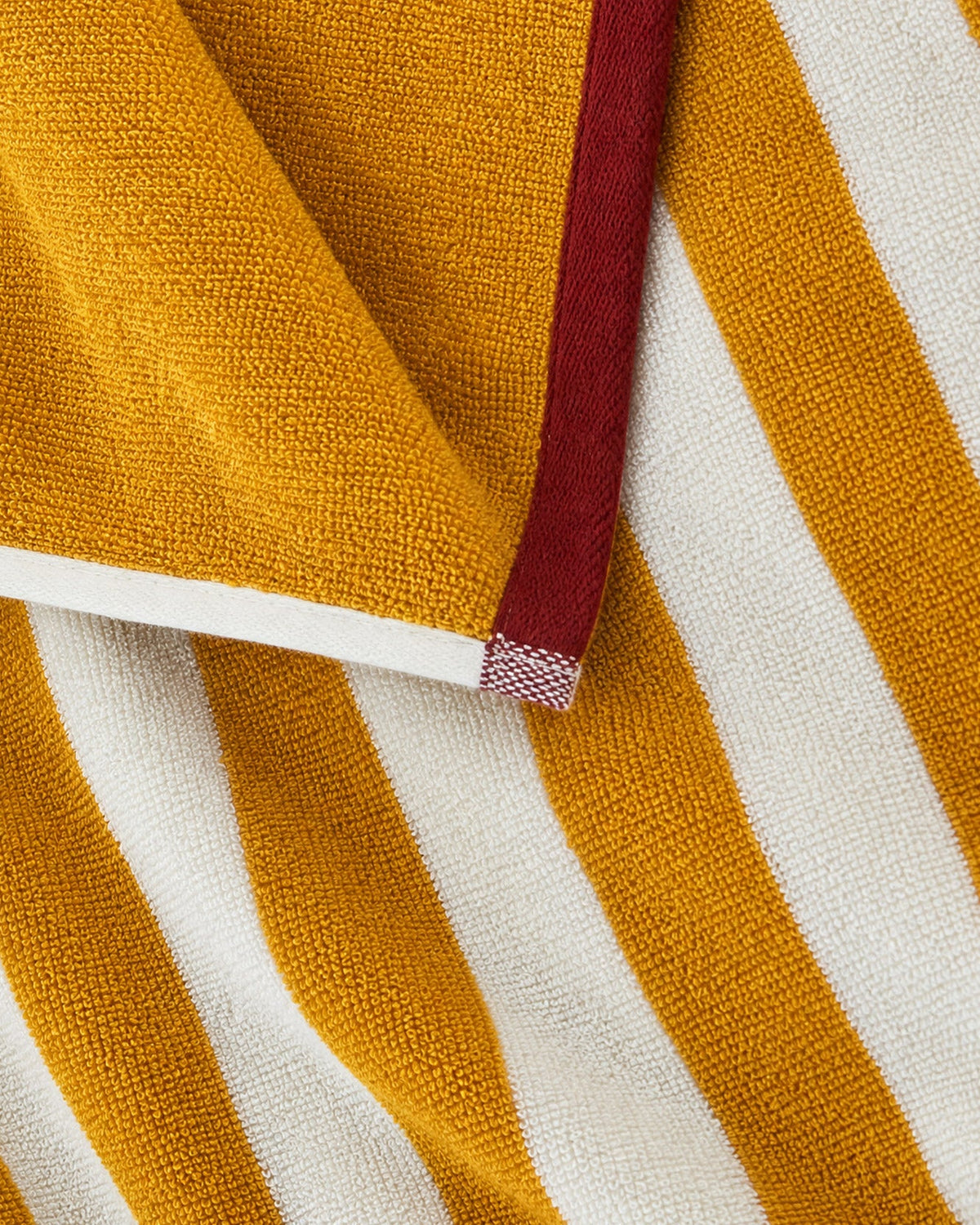 Close-up of ochre and white striped towel with red ribbon trim
