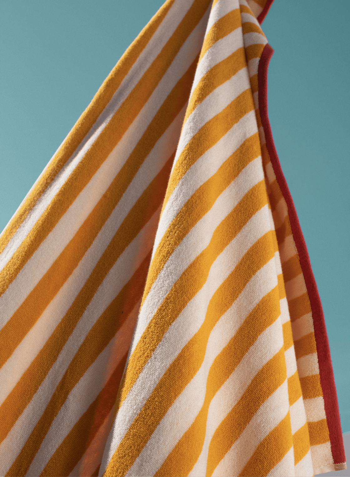 Draped reversible beach towel with ochre and white stripes and red trim