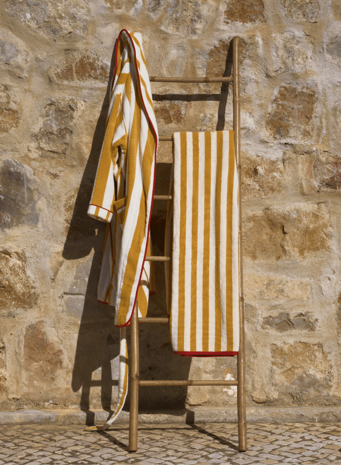 Reversible beach towel on chair, striped and solid ochre sides with red trim