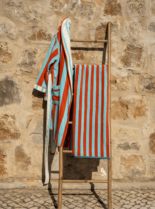 Reversible beach towel folded on a chair, showing aqua and orange vertical stripes
