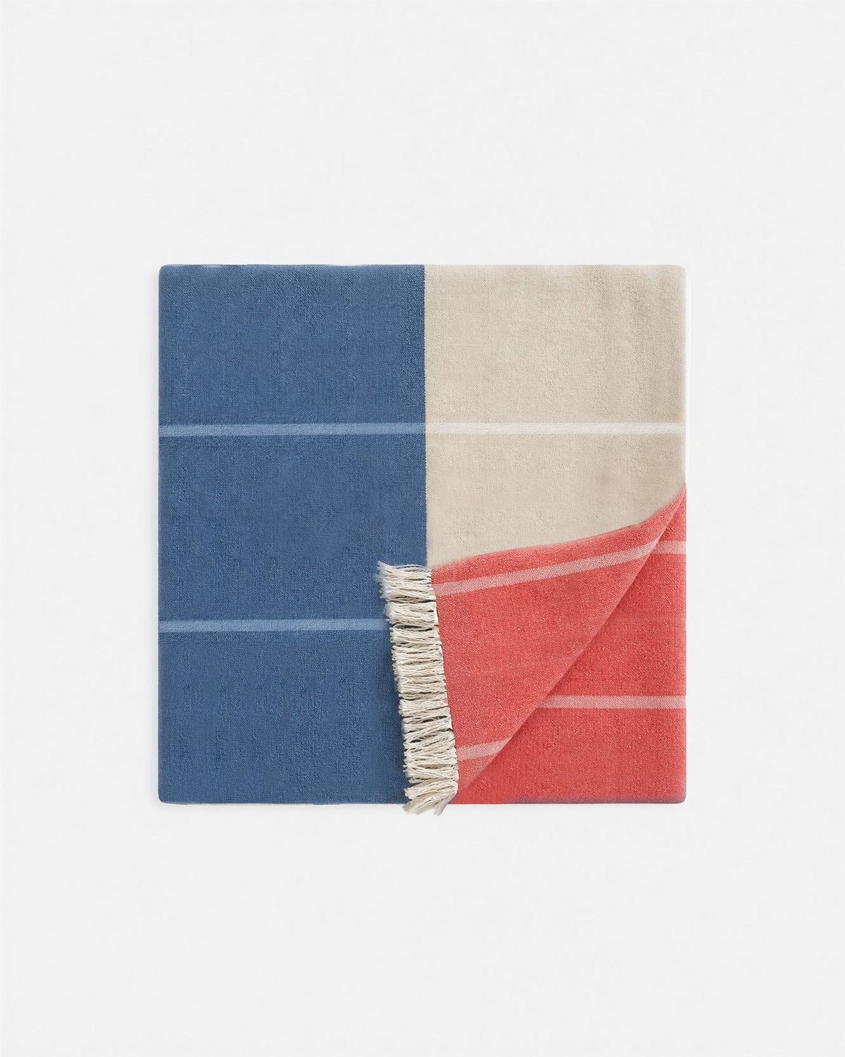 Reversible beach blanket with blue, cream, and coral-red sections; fringed edge.