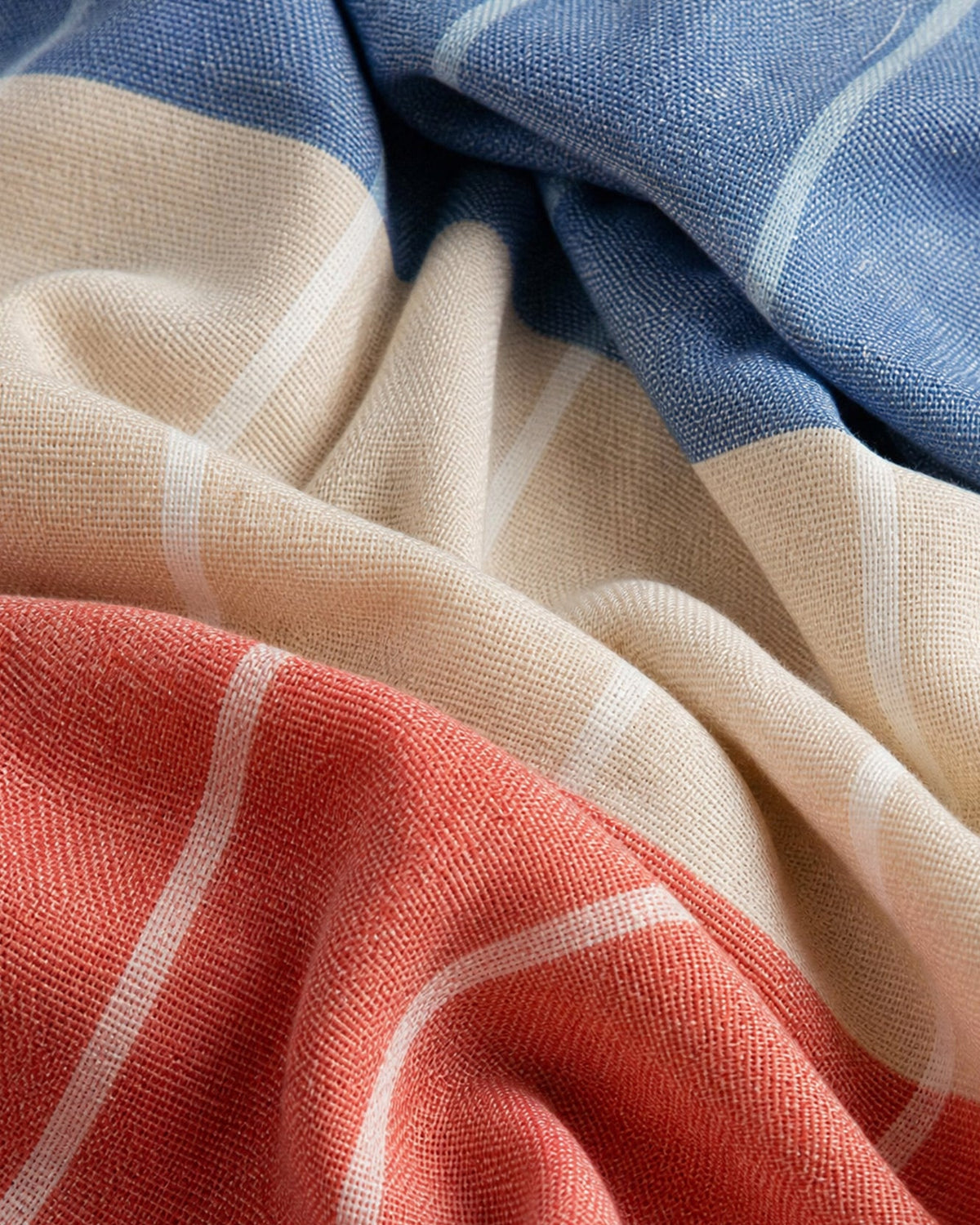 Woven reversible beach blanket fabric with beige, blue, and coral-red plaid stripes.