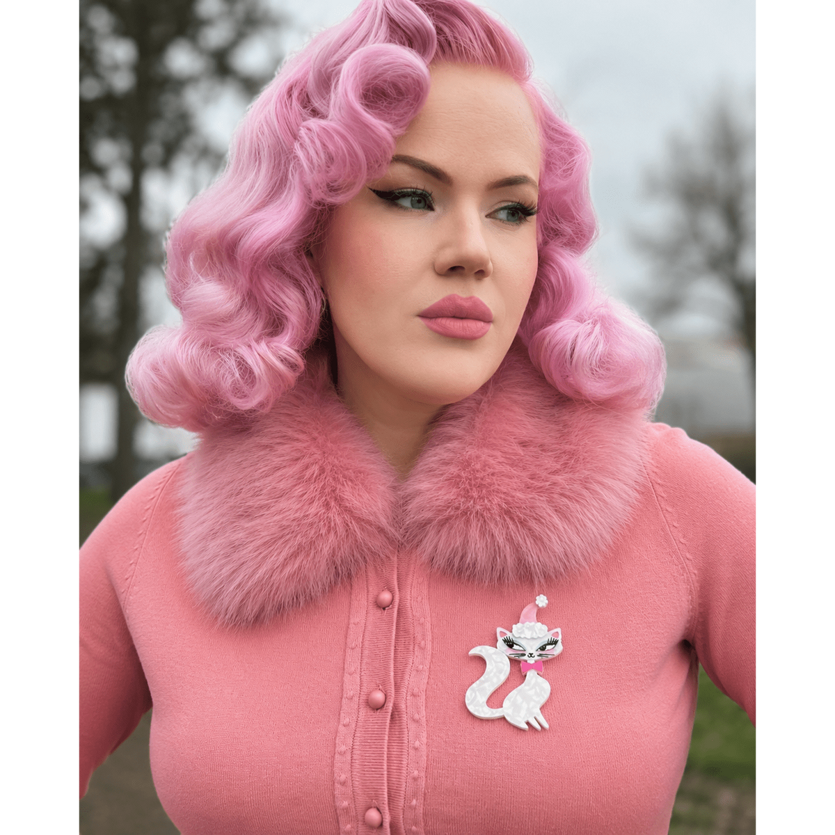 Cat brooch pinned to a pink fuzzy coat with pink cap and bow
