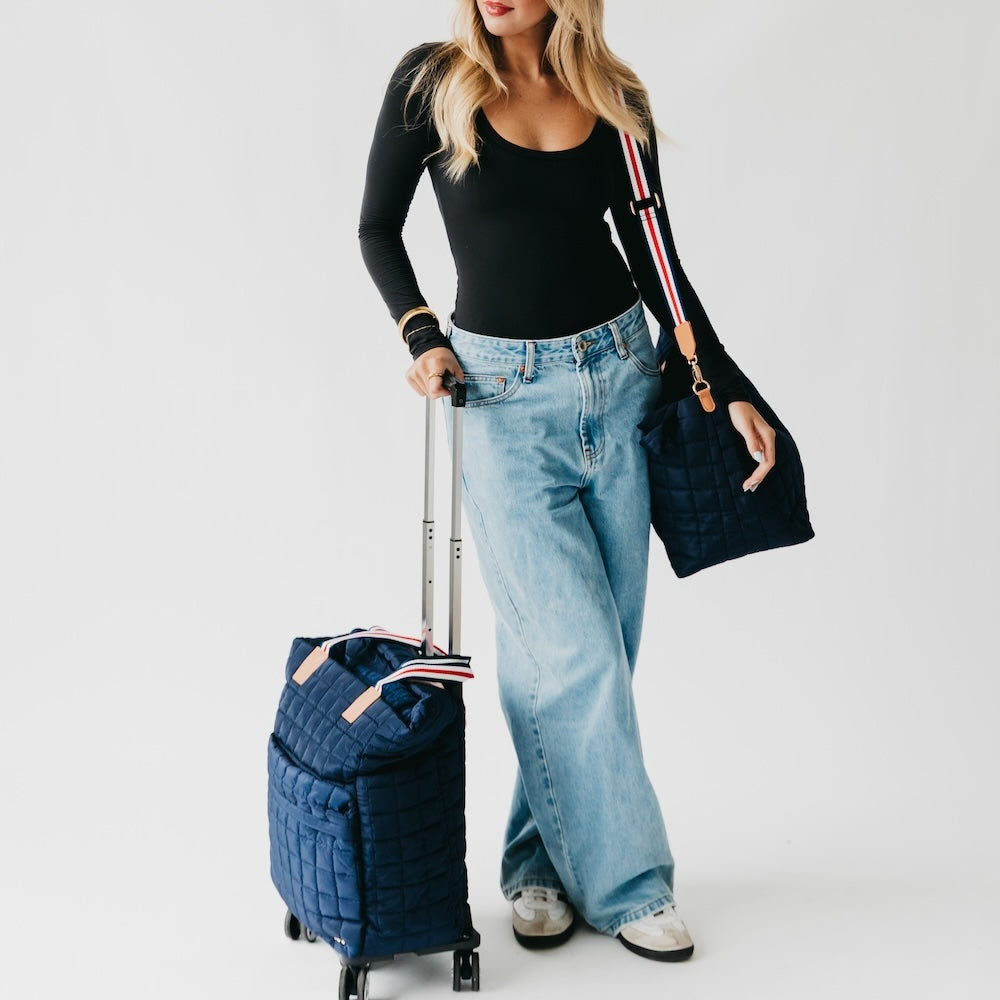 Quilted roller tote bag in dark blue with red-and-white striped strap and wheels