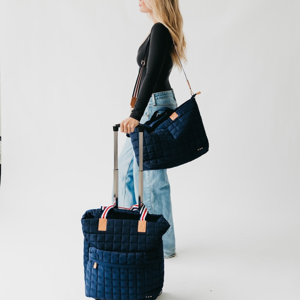 Quilted roller tote bag in dark blue with striped strap trim and rolling wheels