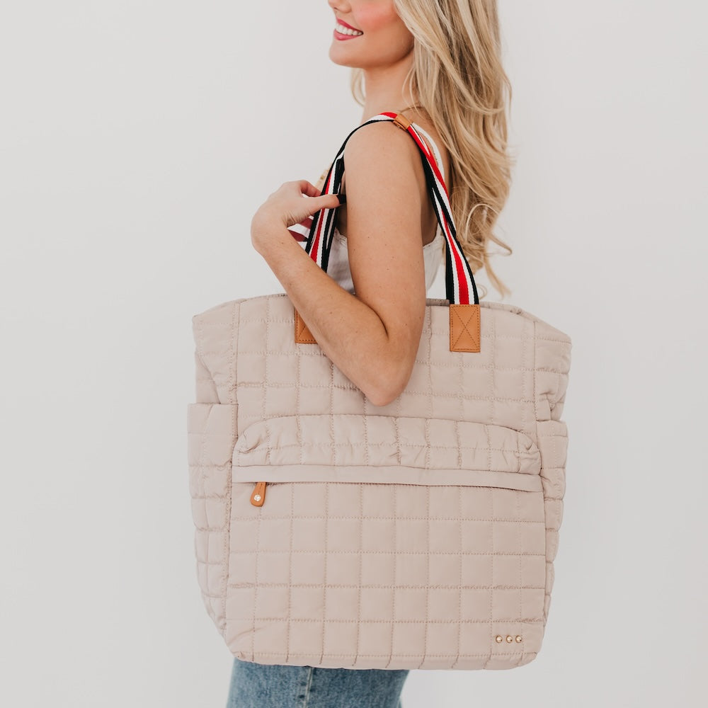 Quilted tan tote bag with striped handles and tan leather-like side accents