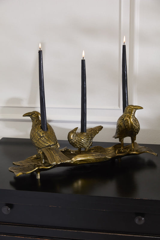 Gold-toned bird candleholder with three upright black candles on perch base