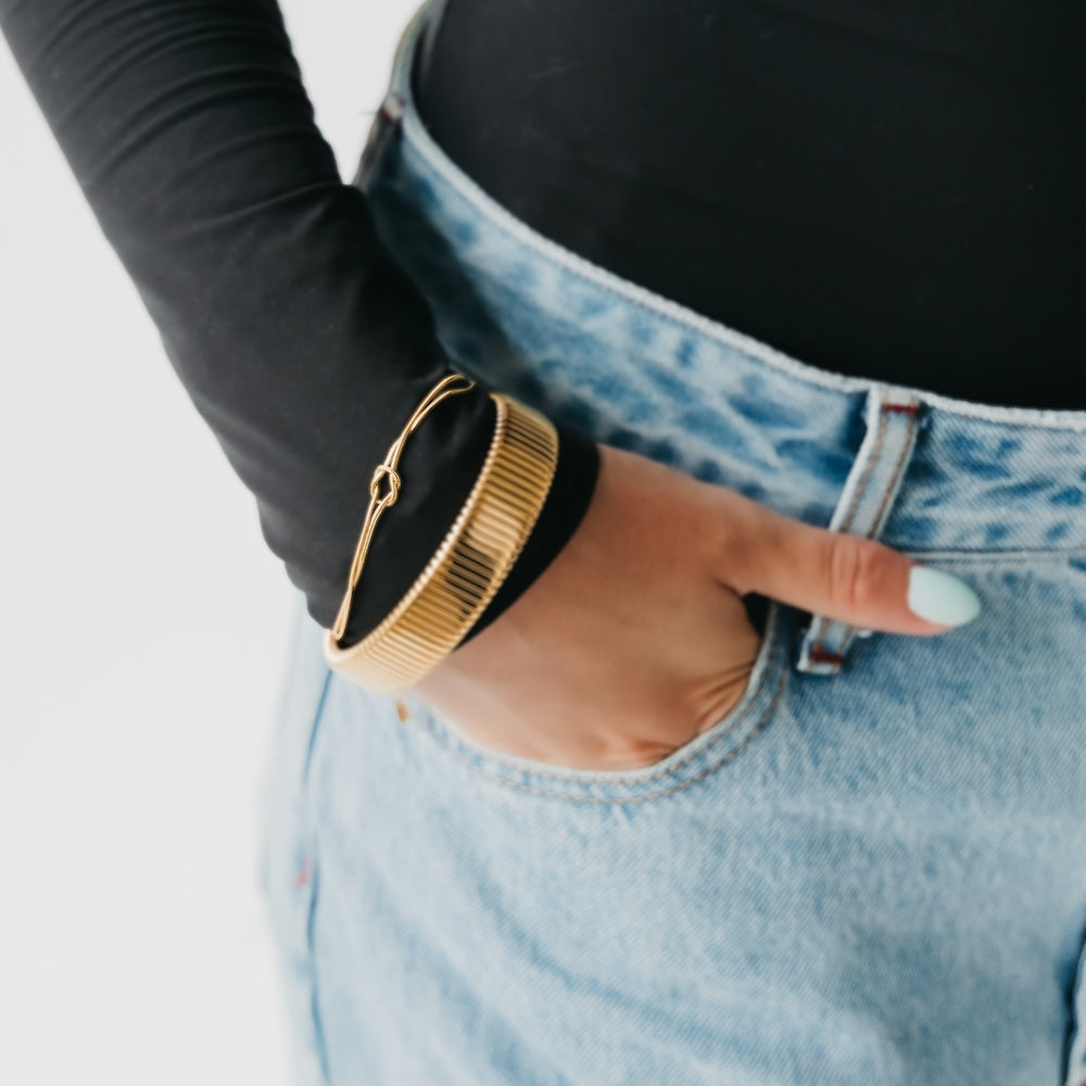Gold-tone bracelet with black band and hook clasp on wrist