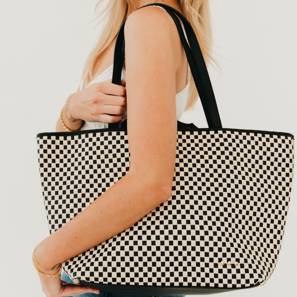 Woven checkered tote bag with black and cream pattern and black top handles