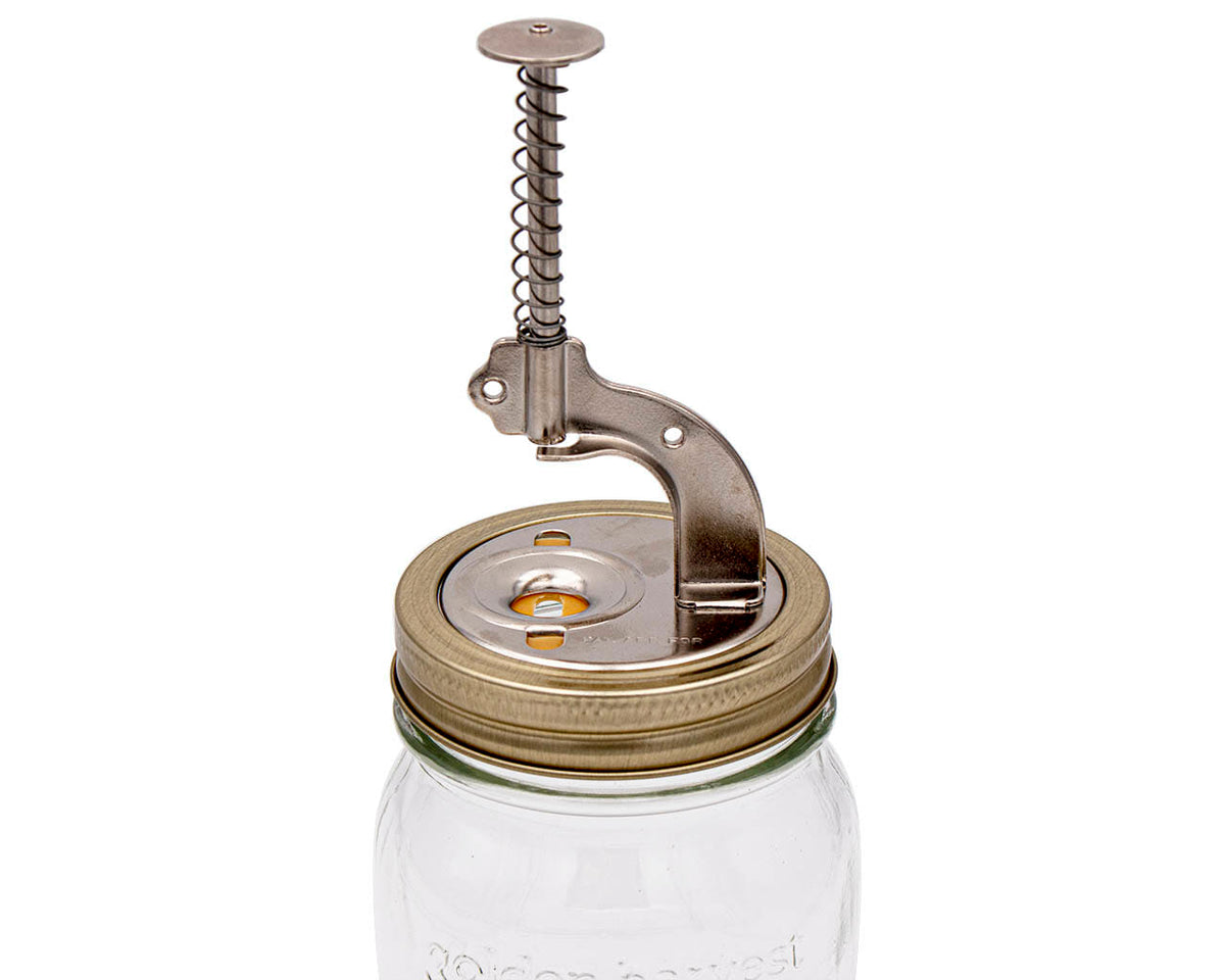 Cherry pitter top with spring lever and press plate mounted on mason jar lid