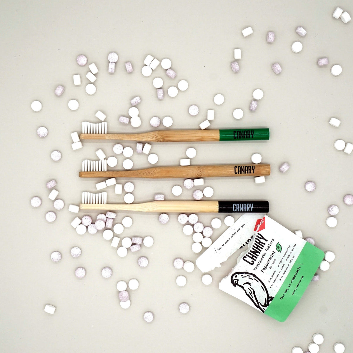 Bamboo toothbrushes and toothpaste tablets beside a packet of peppermint tablets