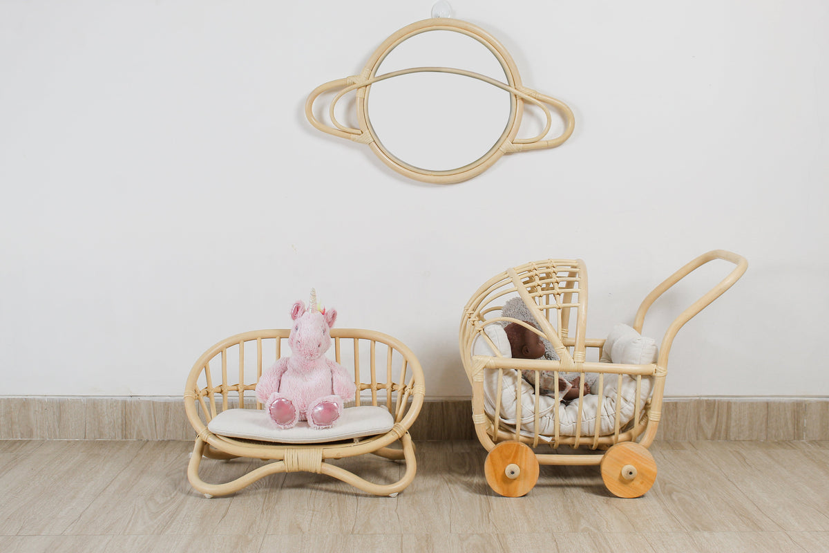 Side view of rattan doll pram showing its woven canopy, handle, and wooden wheels