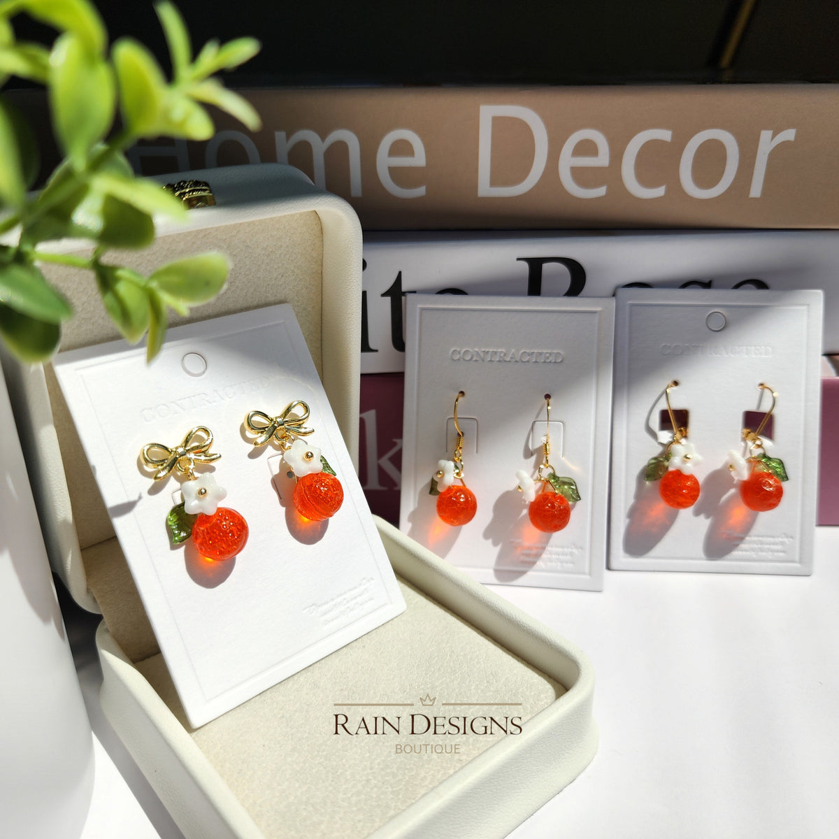 Orange fruit drop earrings with white flower and green leaf, gold bow-tie studs