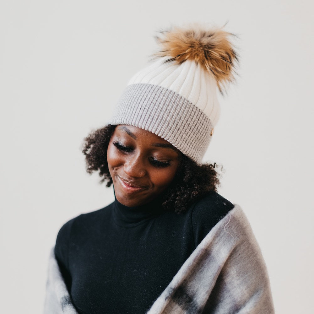 Cream knit beanie with gray stripe and brown fur pom