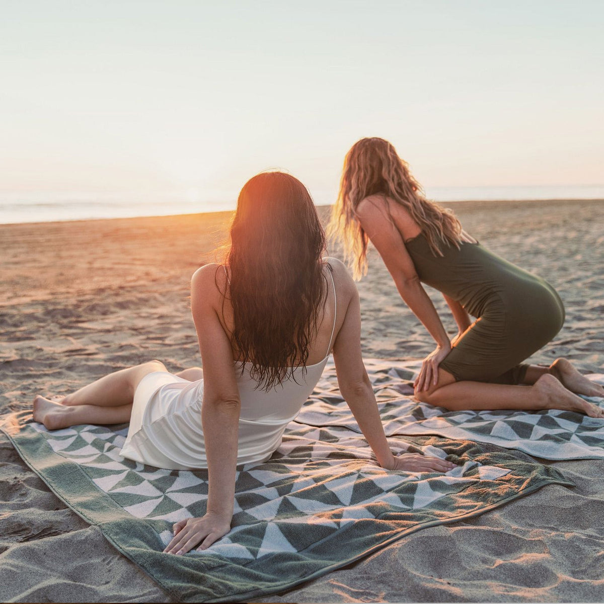 Sage and ecru geometric cotton towels on the beach, with triangle pattern across the fabric.