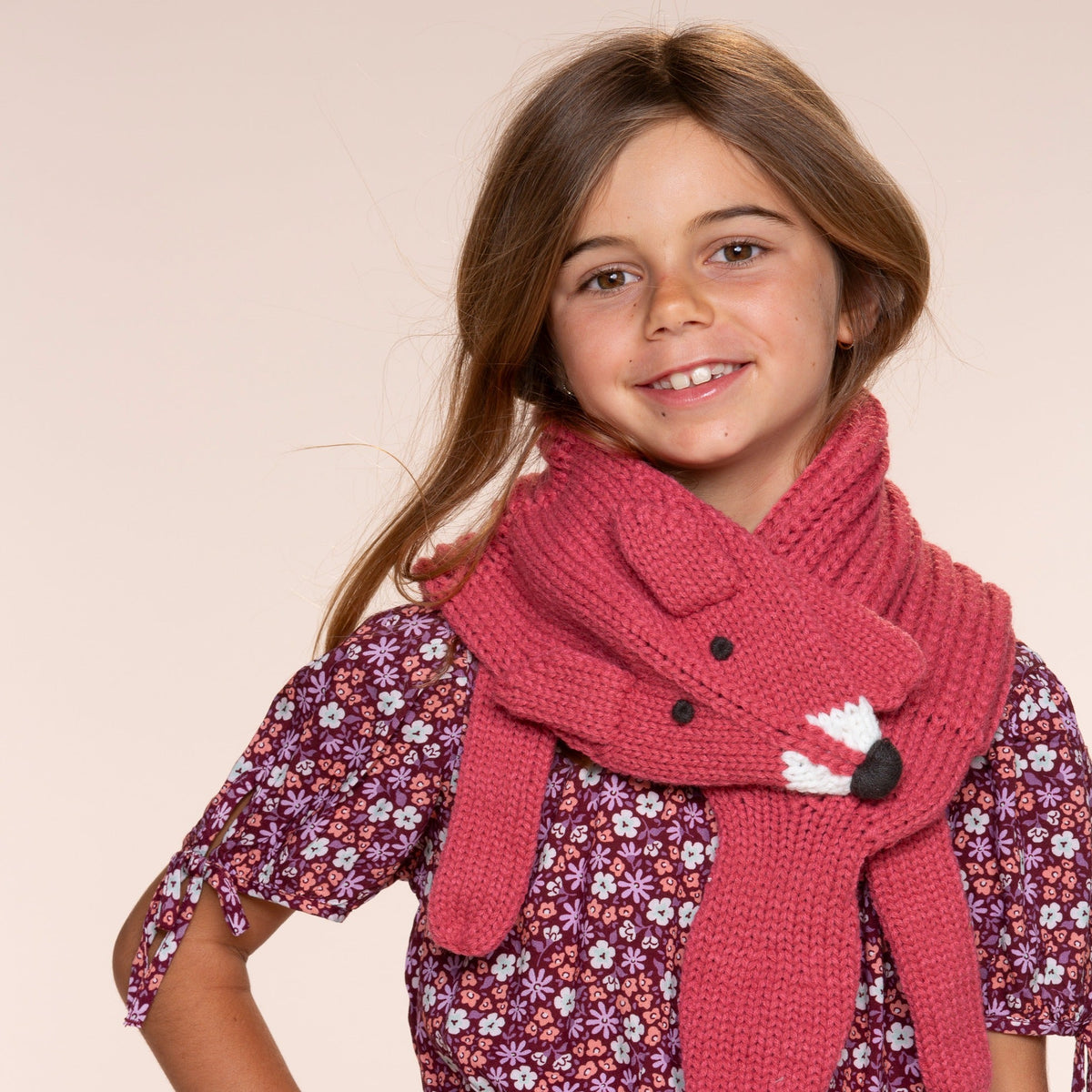 Rust red knit fox scarf worn around a child's neck, with dangling ends and fox face