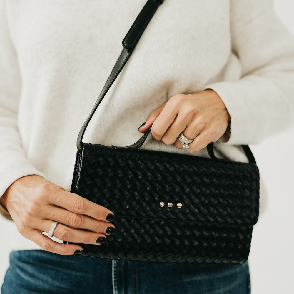 Black woven foldover clutch bag with snap front and chain shoulder strap