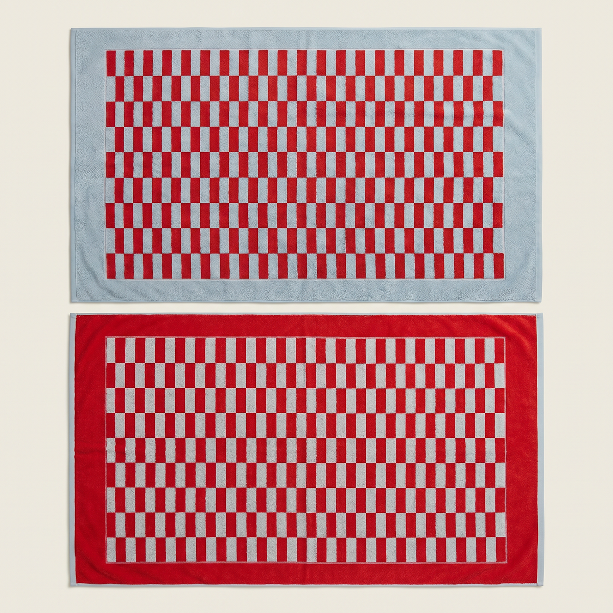 Two folded red and white checkered cotton towels with striped borders