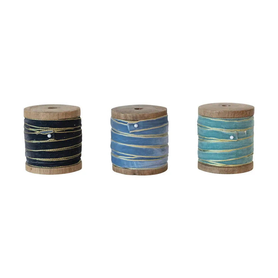 Velvet ribbon metallic-edge spools in navy, blue, and sea foam on wood rolls
