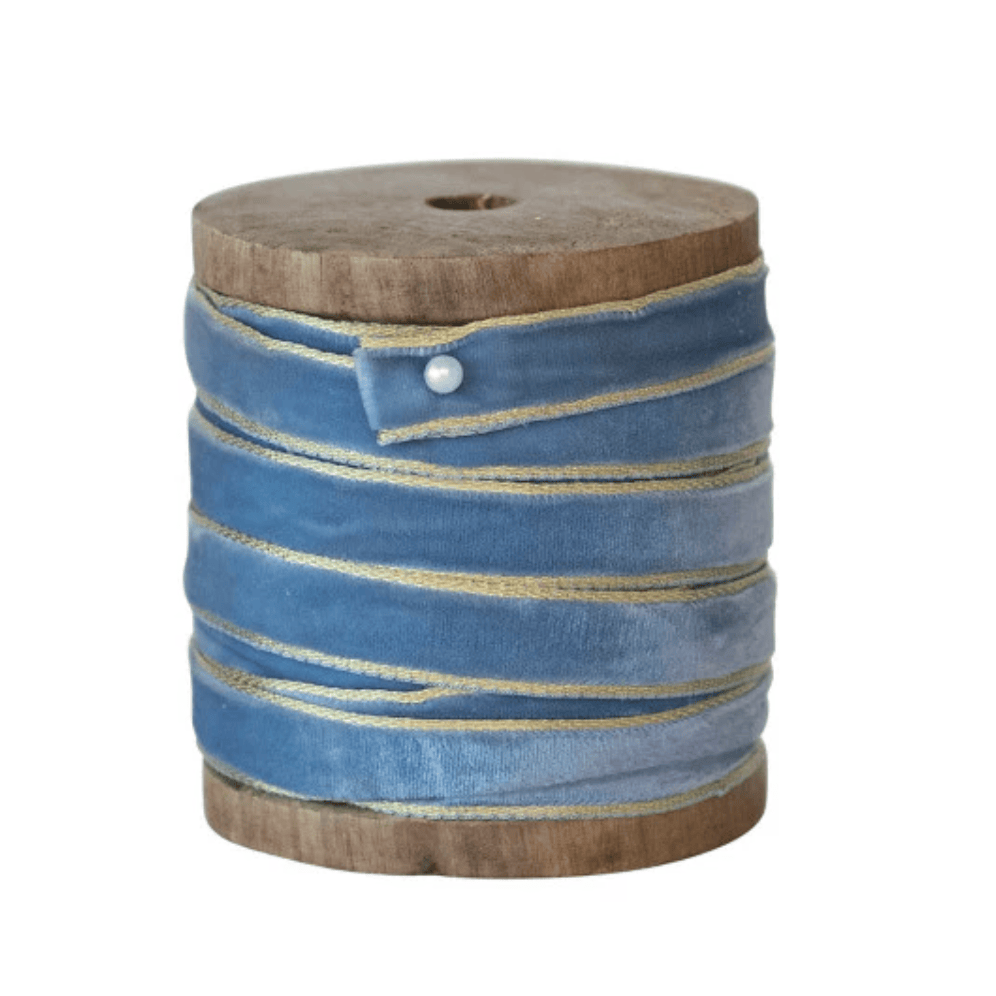 Blue velvet ribbon with metallic edge on a wooden spool