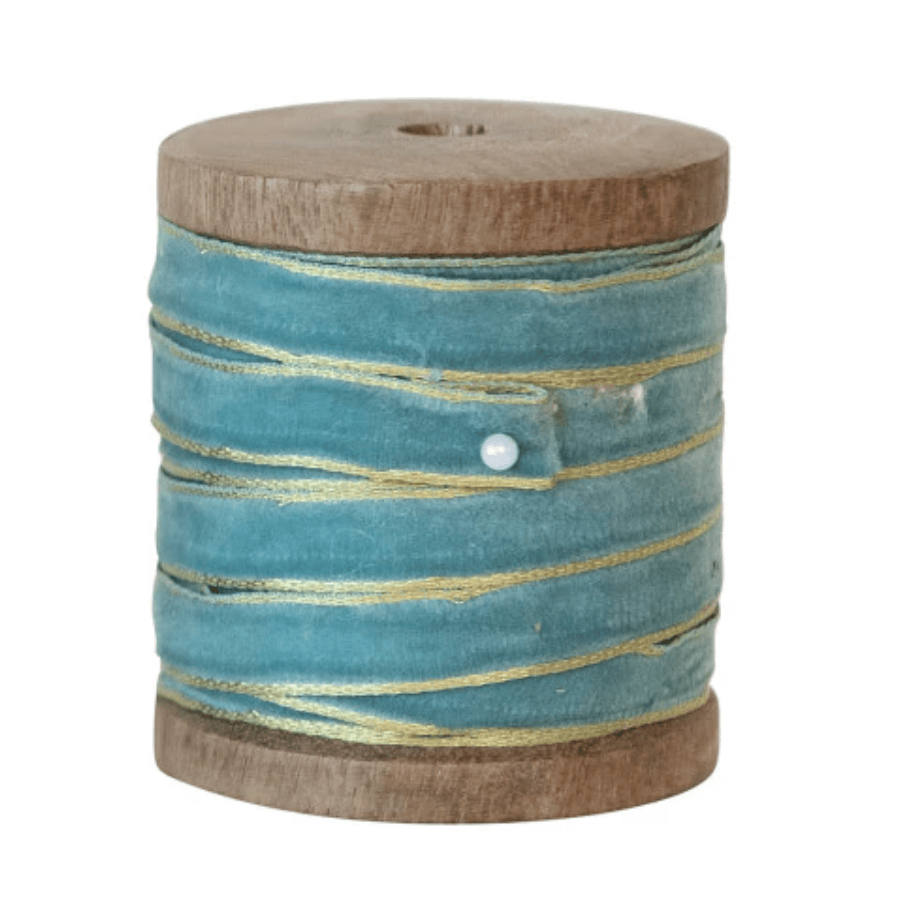 Sea foam velvet ribbon with metallic edge on a wooden spool