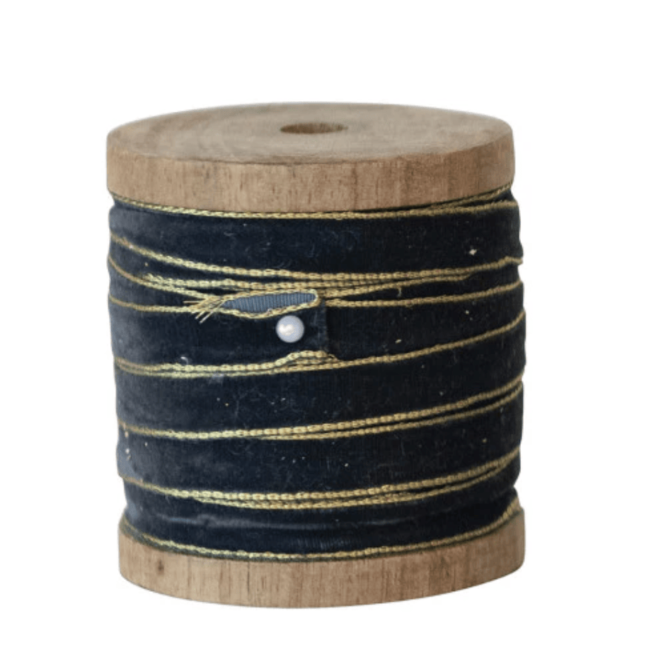 Navy velvet ribbon with metallic edge on a wooden spool