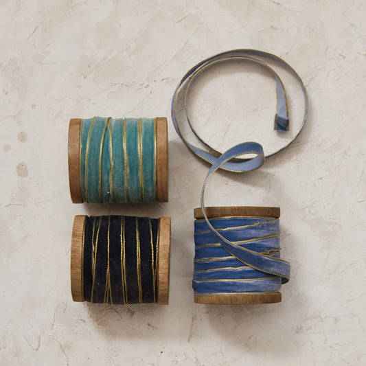 Velvet ribbon with metallic edge spools in blue tones, shown on wood rolls