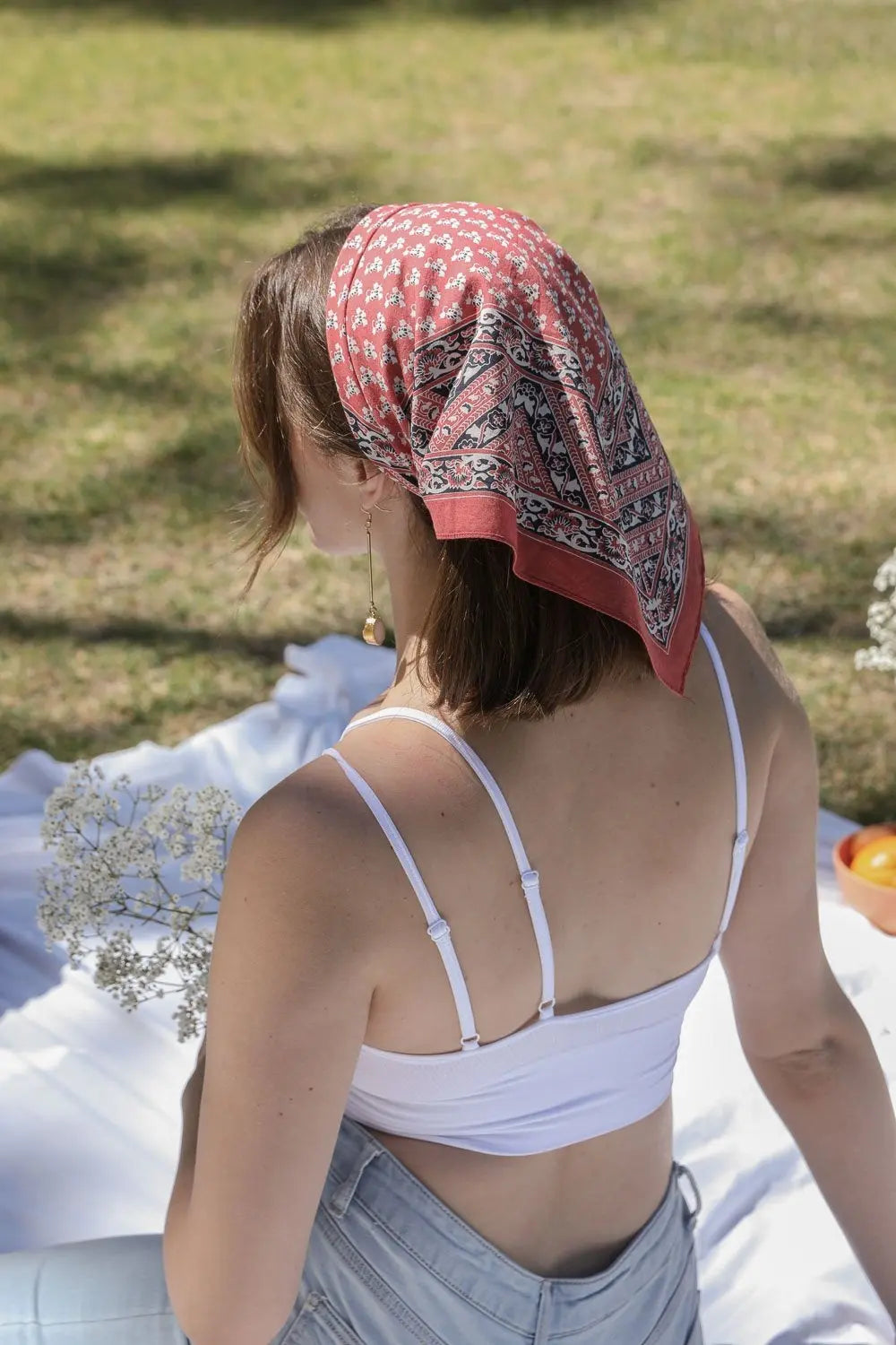 Vine motif bandana scarf in brick red, paisley border, tied in hair (back view)