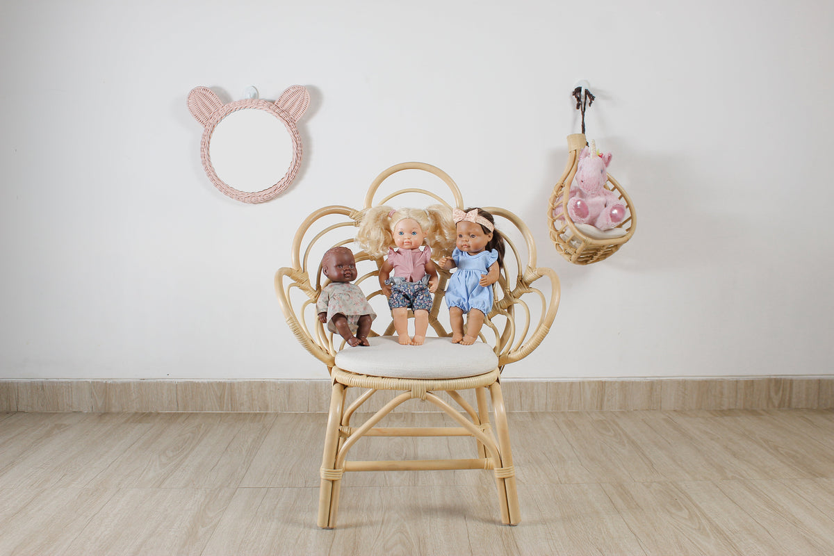 Pink rattan teddy bear wall mirror above a chair with dolls