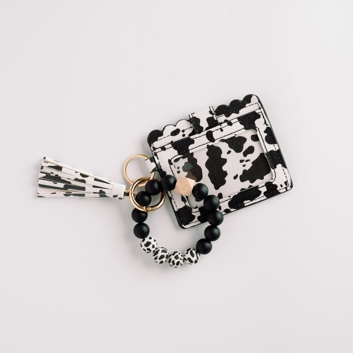 Black-and-white cow print wallet wristlet keychain with tassel and beaded charm ring.