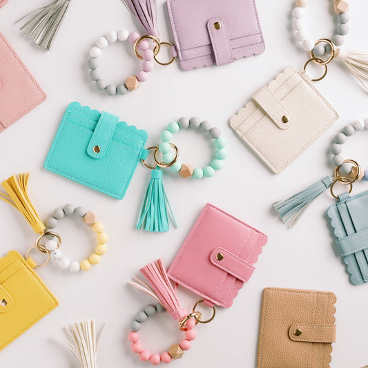 Assorted wallet wristlet keychains with tassels and beaded keyrings in multiple colors